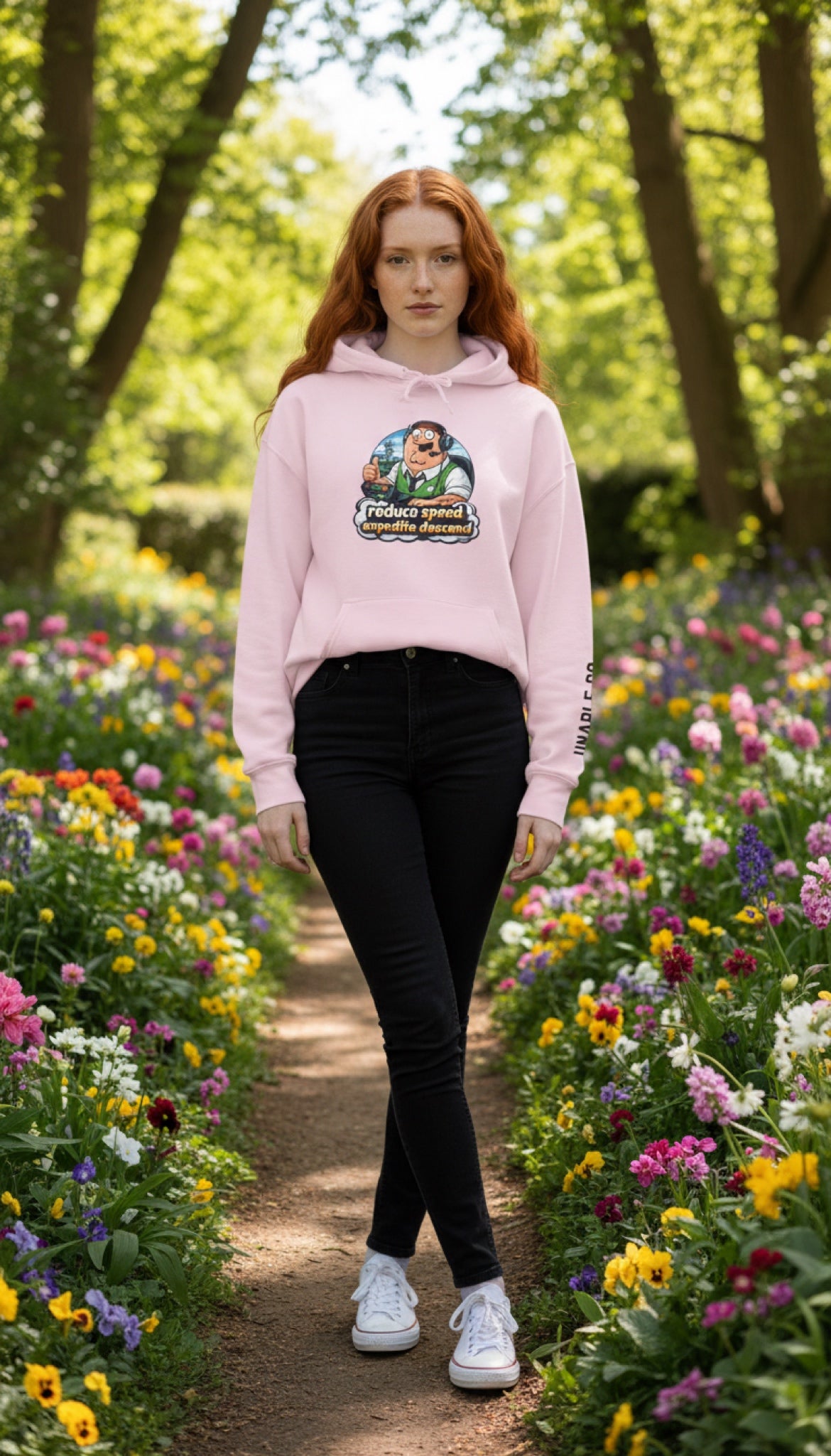 Person wearing a pink hoodie with a graphic design in a garden setting